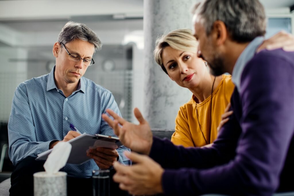 Marriage counselor taking notes while having meeting with a couple in the office.